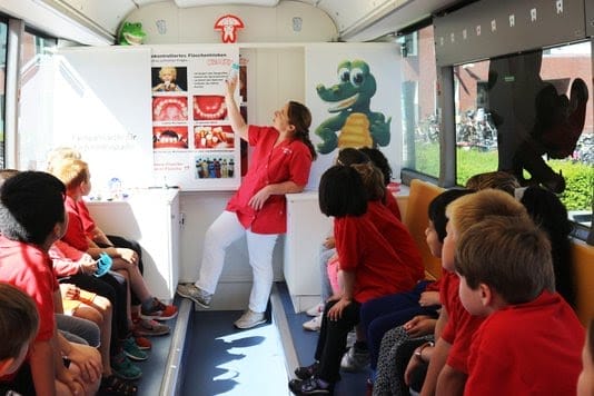 Eerste schoolklas wordt in de Krockybus geïnformeerd over gebitsonderhoud door Dr. Christina von Massow. Foto: Tess Fluit